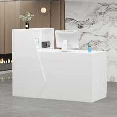 a white reception counter in front of a fireplace with two monitors on it's sides