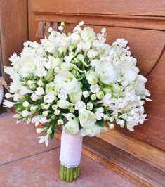 a bouquet of white flowers sitting on the ground next to a wooden door with a teddy bear