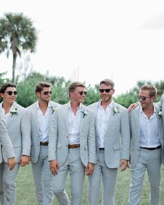 a group of men standing next to each other wearing suits and sunglasses on their heads