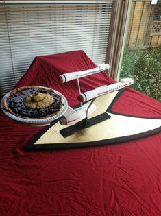 a star trek cake on top of a bed in front of a window with blinds