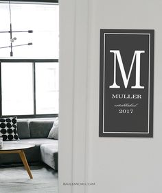 a living room filled with furniture and a wall mounted monogrammed sign on the wall