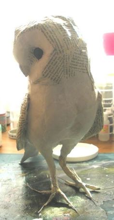 a bird is standing on the table in front of some paint and paper machs