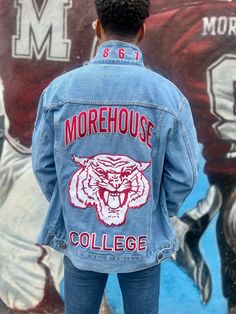 The Homecoming Denim Jacket, a customer favorite, is more than just a name. This lightweight jacket, suitable for all seasons, boasts unique features that set it apart. MOREHOUSE COLLEGE is embroidered on the backside in maroon and is outlined in white with a 3D grey shadow effect.  The Maroon Tiger logo is embroidered on the back and center.  The college's founding year, 1867, is embroidered on the collar in maroon and outlined in white. The sleeves are adorned with original Chicer Collegiate logo patches created exclusively for Morehouse College. The Chicer Collegiate sunglasses logo is embroidered on the upper right sleeve. The front of the jacket is unembellished and has two waist pockets and two chest pockets with button flap closures.   99% 12 oz. combed ringspun cotton, 1% spandex T Spring Denim Outerwear For College, College Denim Jacket For Fall, Fall Denim Jacket For College, Casual Long Sleeve Denim Jacket For College, Spring Long Sleeve Denim Jacket For College, Casual Spring Denim Jacket For College, Long-sleeved Cotton Denim Jacket For College, Long Sleeve Cotton Denim Jacket For College, Casual Cotton Denim Jacket For College