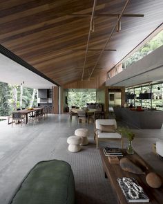 an open living room and dining area with wood ceilinging, white furniture and large windows