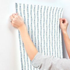 two hands are holding up a piece of fabric that has been drawn on the wall