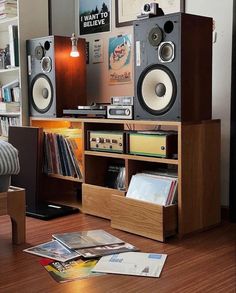 an entertainment center with speakers, bookshelf and magazines on the floor in front of it