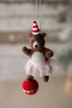 a brown teddy bear wearing a red and white party hat hanging from a christmas ornament