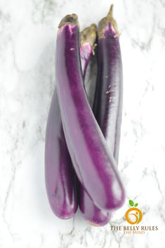 three purple eggplant on a marble surface