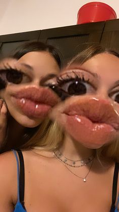 two young women with fake lips are looking in the mirror and making funny face expressions