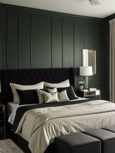 a bedroom with dark green walls and white bedding, along with a bench in front of the bed