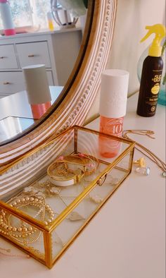 a gold jewelry box sitting on top of a table next to a mirror and bottle