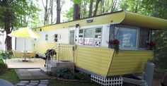 a yellow and white mobile home in the woods