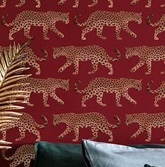 a red wall with gold leopards on it and a palm tree in the foreground