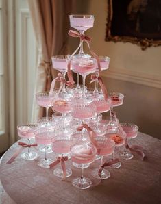 a table topped with lots of wine glasses filled with pink liquid and covered in bows