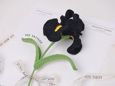 a crocheted black flower sitting on top of a piece of paper