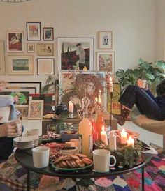 two people are sitting in a living room with candles and pictures on the wall behind them