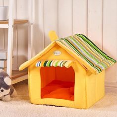 a small dog house next to a teddy bear on the floor in a room with white walls