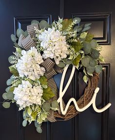 a wreath with white flowers and the word love hanging from it's front door