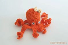 an orange crocheted octopus with blue eyes on it's head and tail