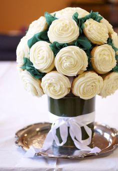 a bouquet of white roses in a vase on a table with a silver platter