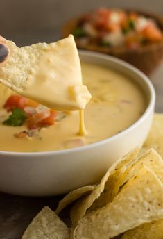 a tortilla chip being dipped into a bowl of quesadilla soup