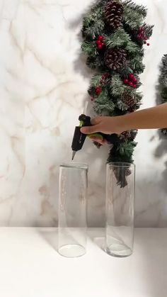 a person holding a spray bottle in front of two glass vases