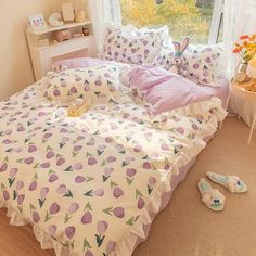 a bed with purple and white flowers on it in a bedroom next to a window