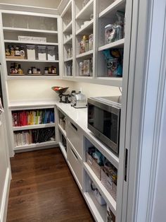 a kitchen with white cabinets and shelves filled with books, magazines, and other items