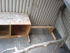 two wooden benches sitting next to each other in front of a metal wall and tree branch