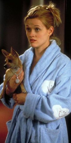 a woman in a robe holding a small dog