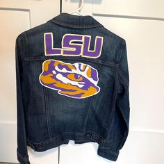 Show off your school spirit with this one-of-a-kind hand-painted LSU Tigers jean jacket! Perfect for game days, tailgating, or any casual outing, this jacket is a must-have for every true fan. With a custom design that celebrates the pride of the Louisiana State University , this jacket combines fashion and fandom in the best way possible. - Jacket Style: Classic denim jacket, Large, Old Navy - Material: 100% cotton denim - Design: Hand-painted LSU Tigers logo and artwork Spring Cotton Denim Jacket For College, School Spirit Cotton Outerwear For Game Day, Game Day Fashion, Lsu Tigers Logo, University Apparel, Tailgate Outfit, Louisiana State University, Day Fashion, Classic Denim Jacket