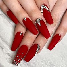 a woman's hand with red nail polish and diamond decorations on it, holding onto her nails