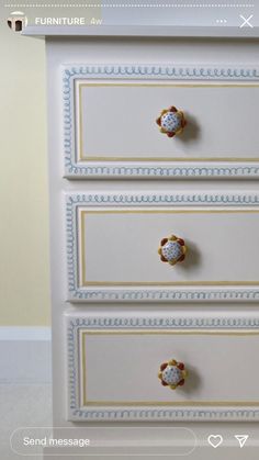 a white dresser with three drawers and knobs