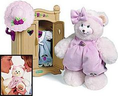 a white teddy bear with a pink dress and hat next to a doll's wardrobe