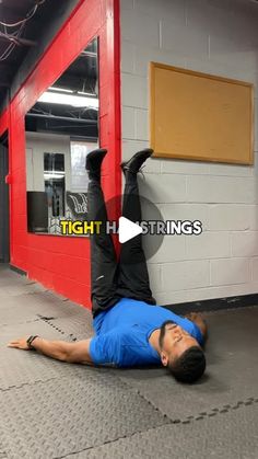 a man laying on the ground in front of a red wall with his hands up