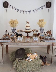 a table topped with lots of cake and desserts on top of hay bales