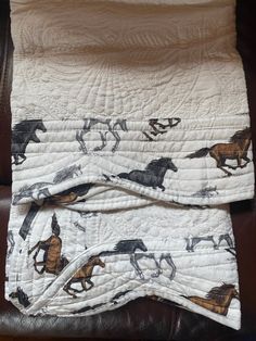 two quilts with horses on them sitting on a leather chair next to a pillow