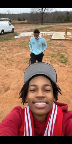 a woman taking a selfie in front of two other people on a field with one person wearing a hat