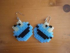 a pair of blue and black beaded earrings sitting on top of a wooden table