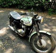 a green and white motorcycle parked in front of some bushes