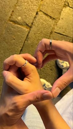 two hands holding onto each other while they are sitting on the ground with their fingers together