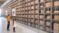 two people standing in front of a large display of cheeses on metal shelving