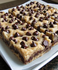 chocolate chip cookie bars sitting on top of a white square plate, ready to be eaten