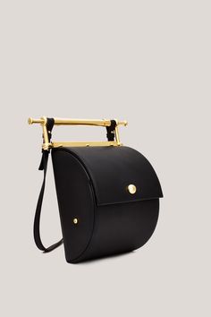 This is Thana. Handmade in Italy, using only the highest quality materials, Thana’s unique shape and gold-coated hardware make it an absolute stand-out. The brand’s signature decorative handle is undoubtedly unique, serving as both an intentional design detail and functional element to the bag. With an adjustable, removable strap the Thana can be styled cross-body, over the shoulder or as a chic handbag. Featuring our signature large interior compartment with pearl detail. Luxury Gold Bucket Bag For Daily Use, Luxury Handheld Bucket Bag For Office, High-end Daily Use Bucket Bag With Gold-tone Hardware, Luxury Handheld Satchel With Metal Hardware, Designer Gold Bucket Bag For Everyday Use, High-end Gold Bag With Top Carry Handle, High-end Gold Bags With Top Carry Handle, Designer Gold Shoulder Bag With Brass Hardware, Designer Bags With Brass Hardware For Everyday Use