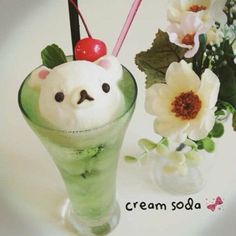 a green drink with a cherry on top in front of white flowers and a flower vase