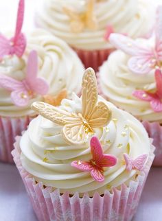 cupcakes with white frosting and pink butterflies on the top one is decorated