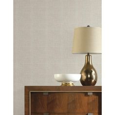 a lamp on top of a wooden dresser next to a white bowl and brown cabinet