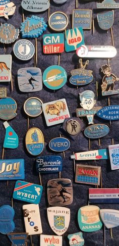 many different badges and pins on a blue cloth covered table with the names of various countries