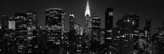 the new york city skyline at night in black and white with skyscrapers lit up