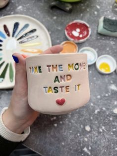 someone holding up a ceramic mug with the words time the money and taste it